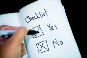 a yes or no check box on paper with a person holding a pen 